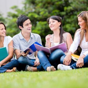 Happy group of students sitting at the park talking